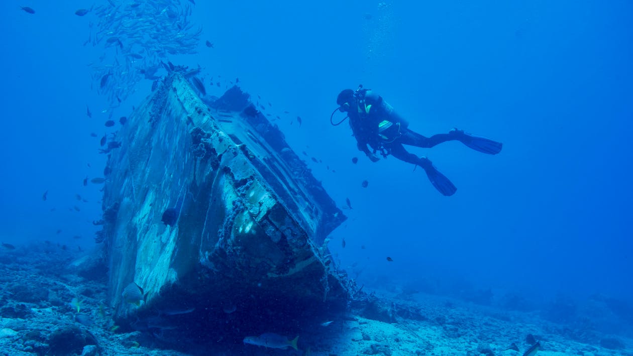 Diver inspecting an underwater shipwreck during a vessel inspection