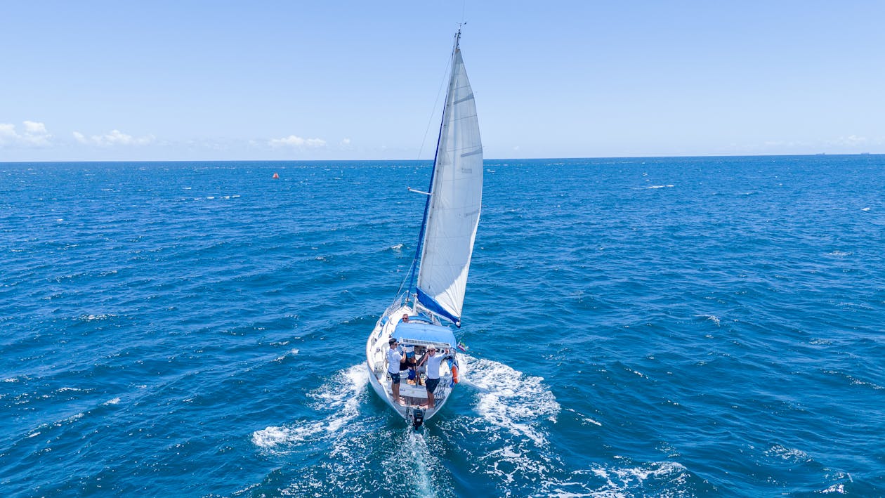 Group of people sailing on a sailboat across vibrant blue water on a sunny day